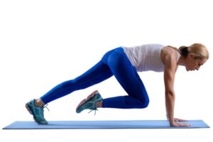 Femme exécutant un exercice mountain climber sur tapis de yoga, contenu typique d'un coach sportif en vidéo